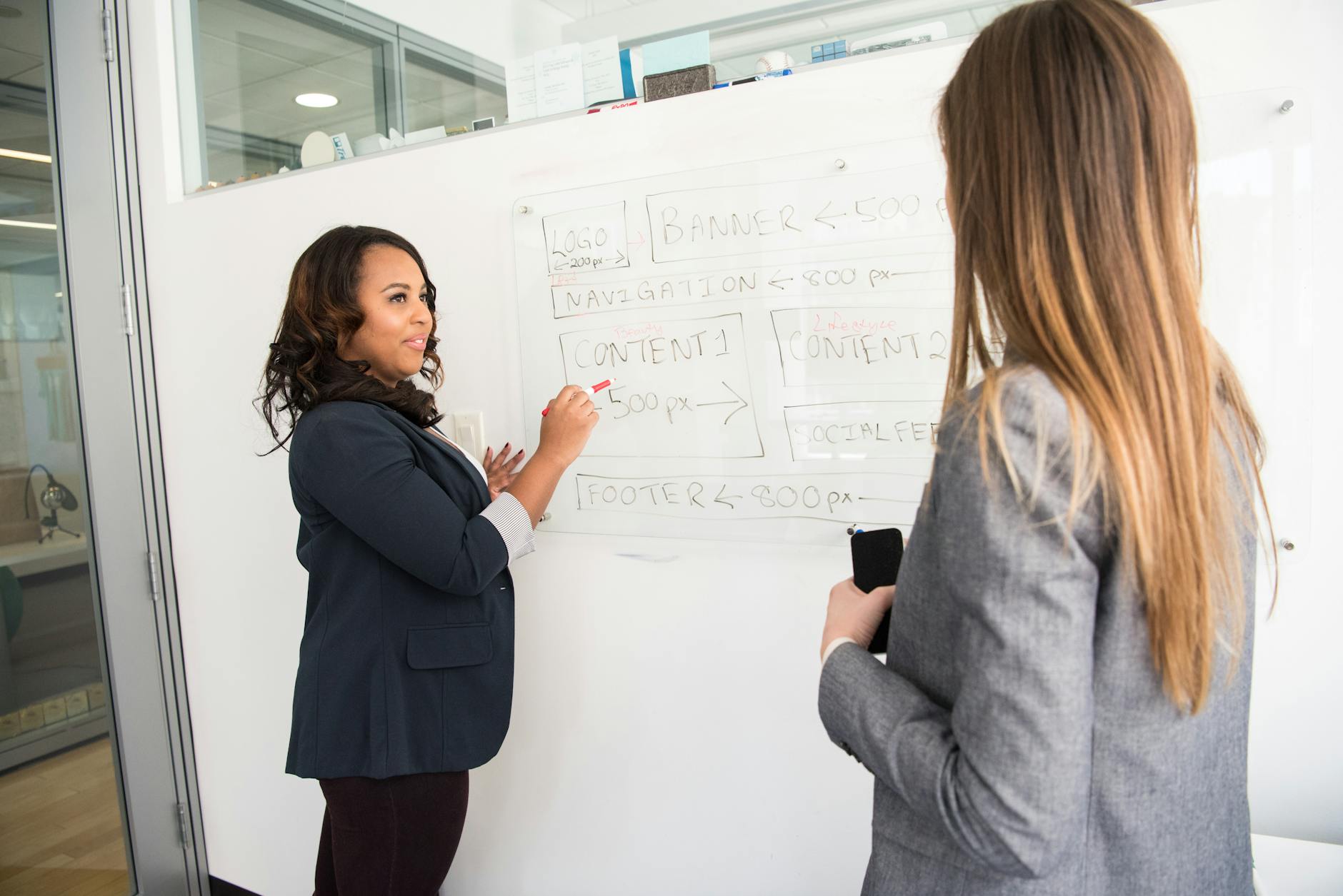 woman in black blazer looking at woman in grey blazer